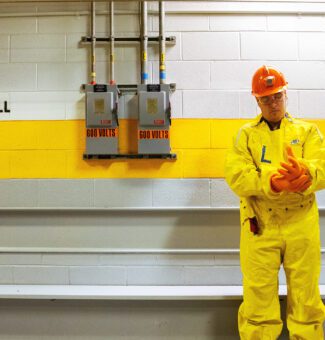 A male worker in protective plastic clothing stands in a hallway within the protected area of a nuclear station.